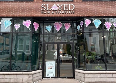 Front view of Slayed Hair And Esthetics in Halifax, Nova Scotia, CA with stylish glass door and gemstone decor.