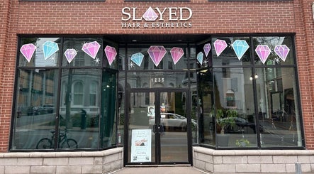 Front view of Slayed Hair And Esthetics in Halifax, Nova Scotia, CA with stylish glass door and gemstone decor.