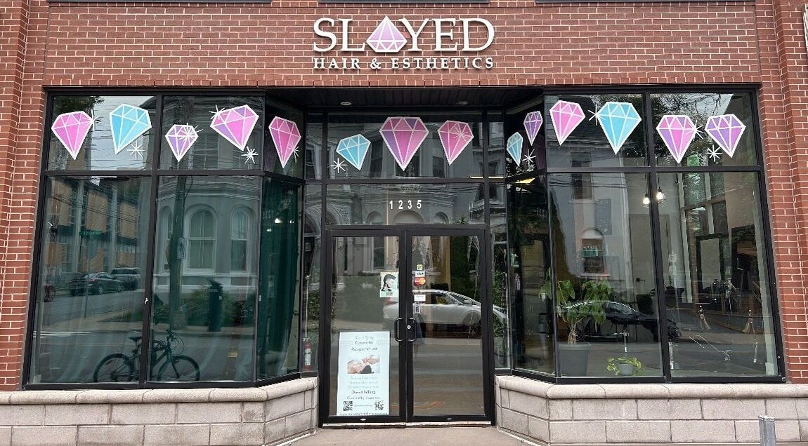 Front view of Slayed Hair And Esthetics in Halifax, Nova Scotia, CA with stylish glass door and gemstone decor.