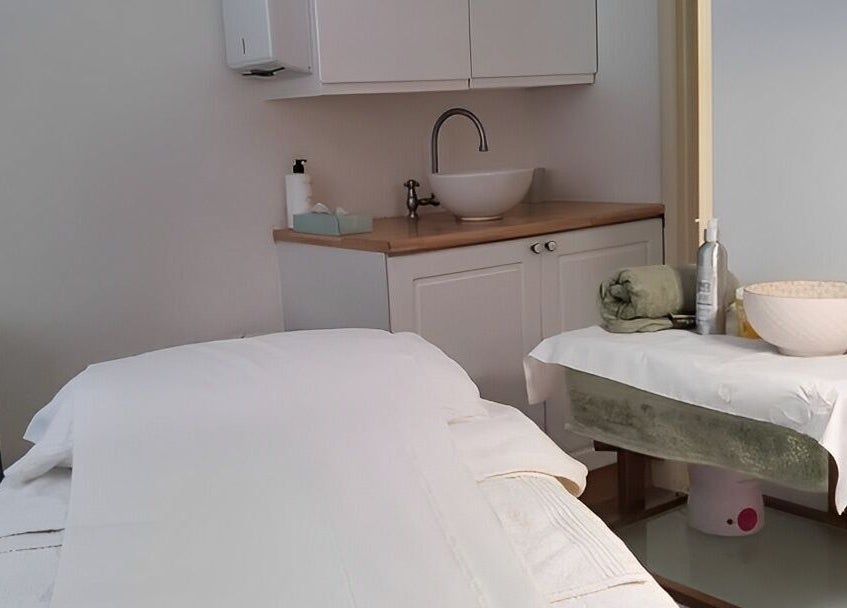 Relaxing treatment room at The Skin Care Clinic, Norwich, England, GB with massage table and sink area.