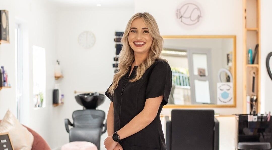 HairbyKellyGrace stylist smiling inside chic salon in Gqeberha, Eastern Cape, ZA.