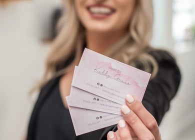 Client holding HairbyKellyGrace business cards in Gqeberha, Eastern Cape, ZA for stylish hair services.