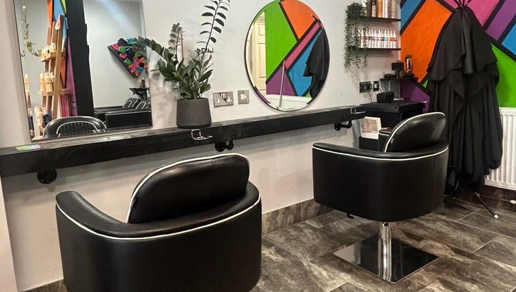 Modern salon interior at Reds in Hull, England, GB featuring stylish black chairs and vibrant wall decor.