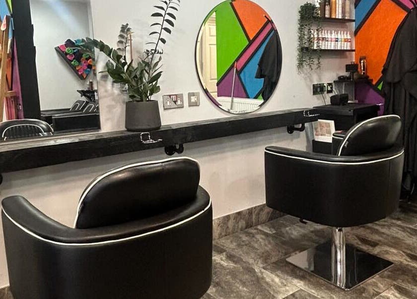 Modern salon interior at Reds in Hull, England, GB featuring stylish black chairs and vibrant wall decor.