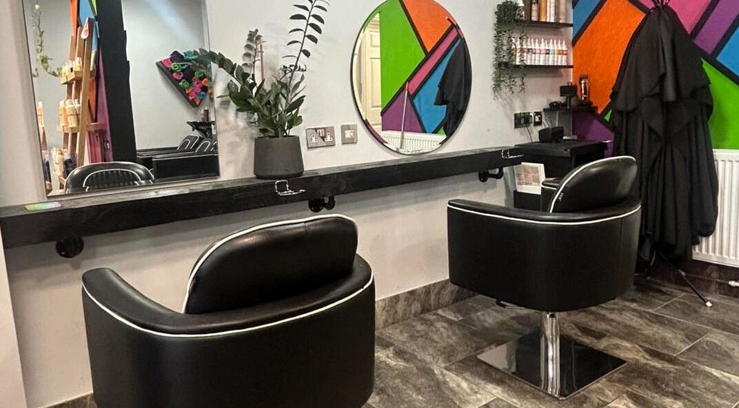 Modern salon interior at Reds in Hull, England, GB featuring stylish black chairs and vibrant wall decor.