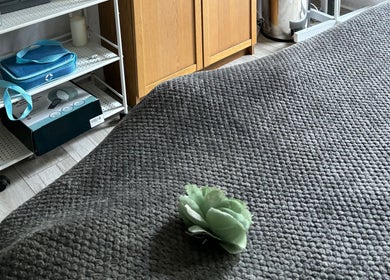 Calm massage room at Kerridwen, Cardiff, Wales, GB with gray linens and green decor.