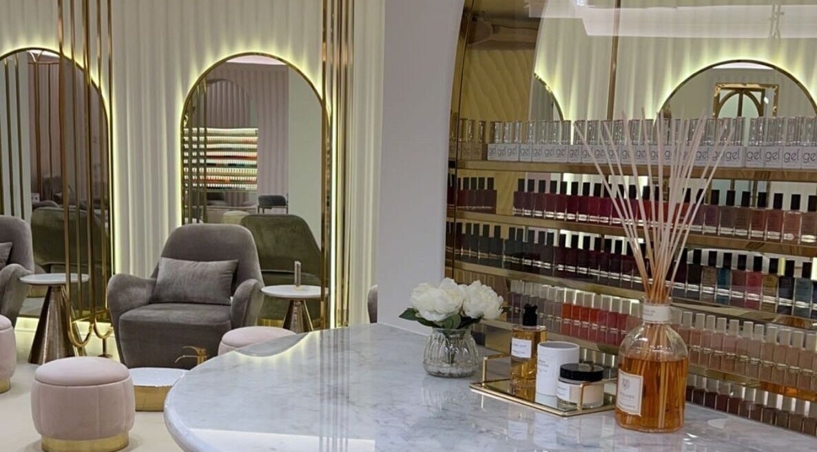 Luxurious interior of Gloss Up Beauty Lounge in Al Ain, AE featuring plush seating and nail polish display.