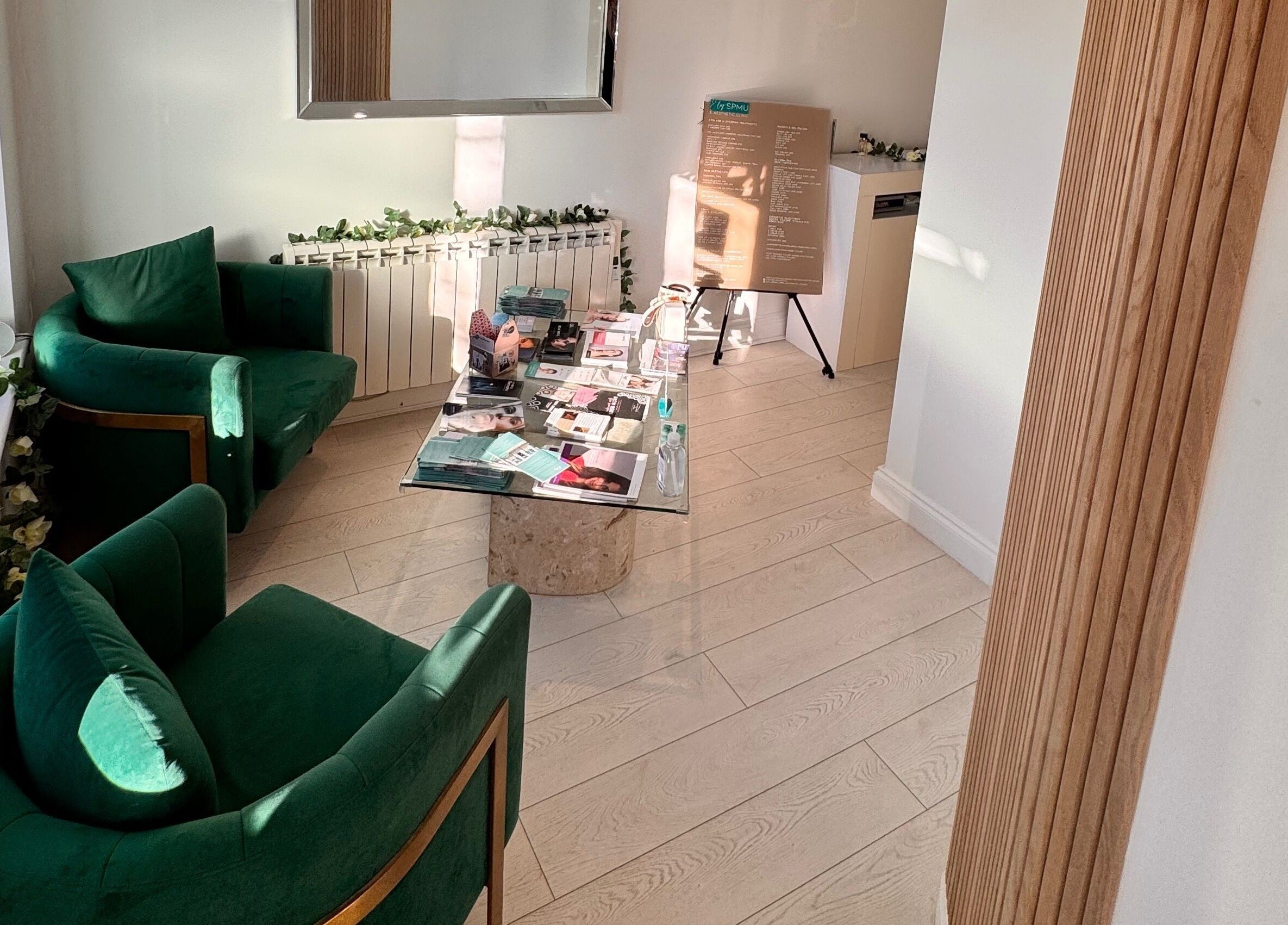 Relaxing seating area at Ely Spmu & Aesthetic Clinic, Ely, England, GB with green chairs and decorated table.