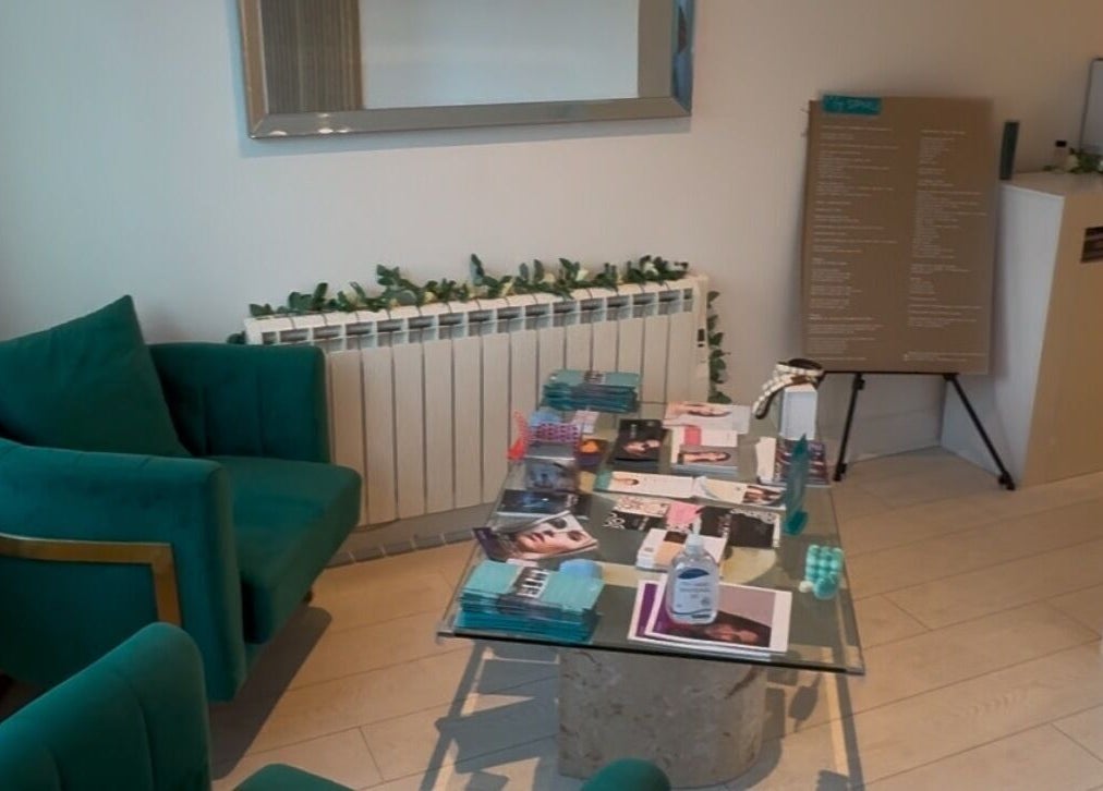 Elegant waiting area at Ely Spmu & Aesthetic Clinic in Ely, England, GB featuring green armchairs and glass table.