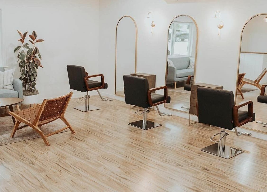 Chic salon interior at Boheme, Ojai, California, US with stylish chairs and mirrors under warm lighting.