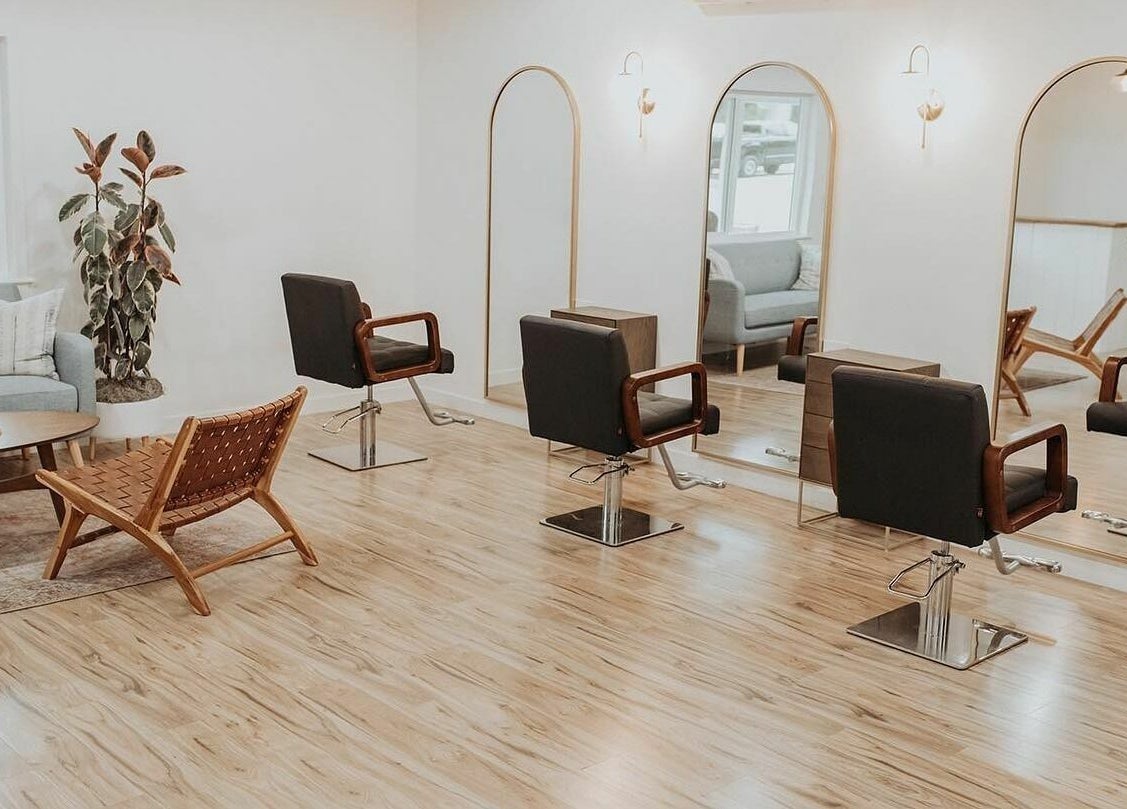 Chic salon interior at Boheme, Ojai, California, US with stylish chairs and mirrors under warm lighting.