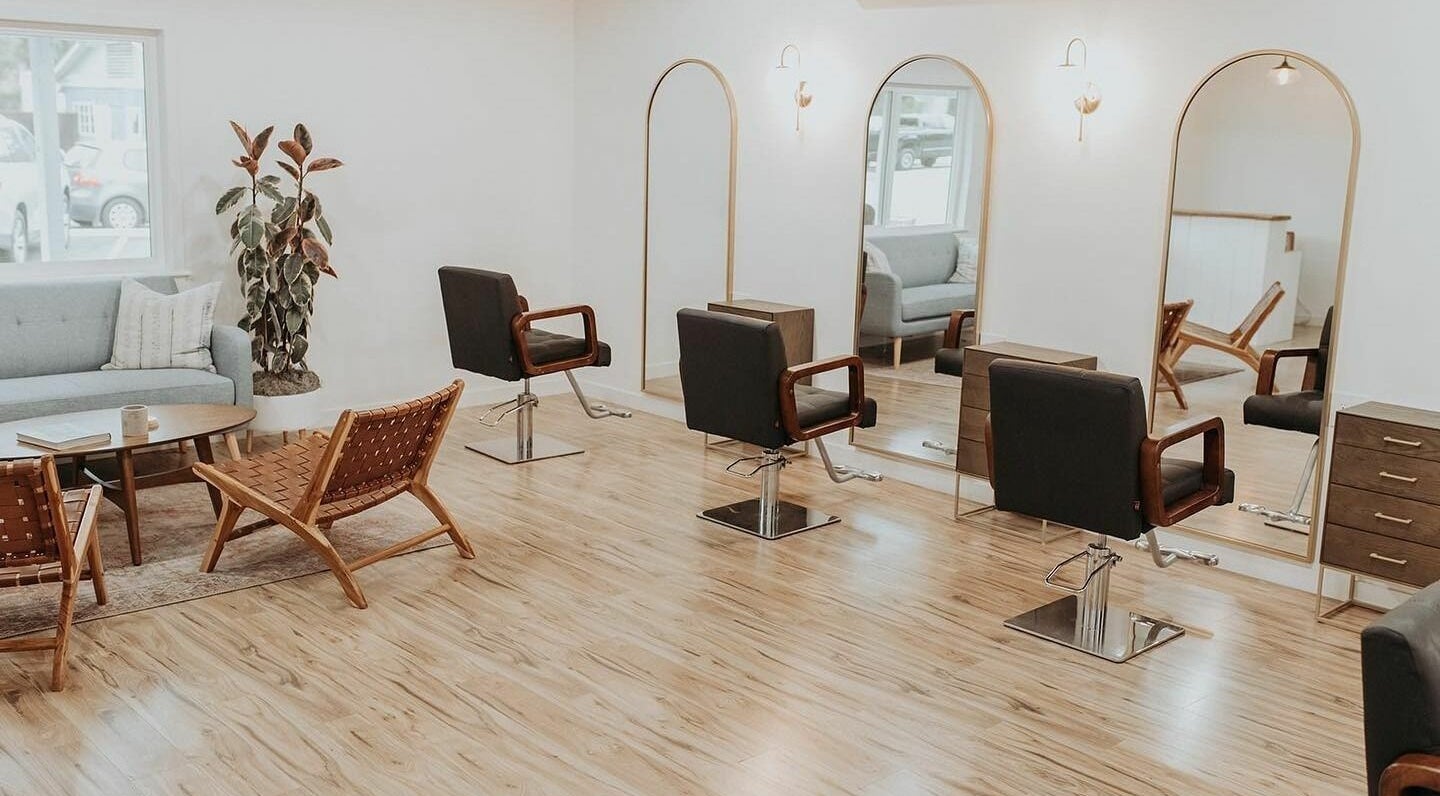 Chic salon interior at Boheme, Ojai, California, US with stylish chairs and mirrors under warm lighting.