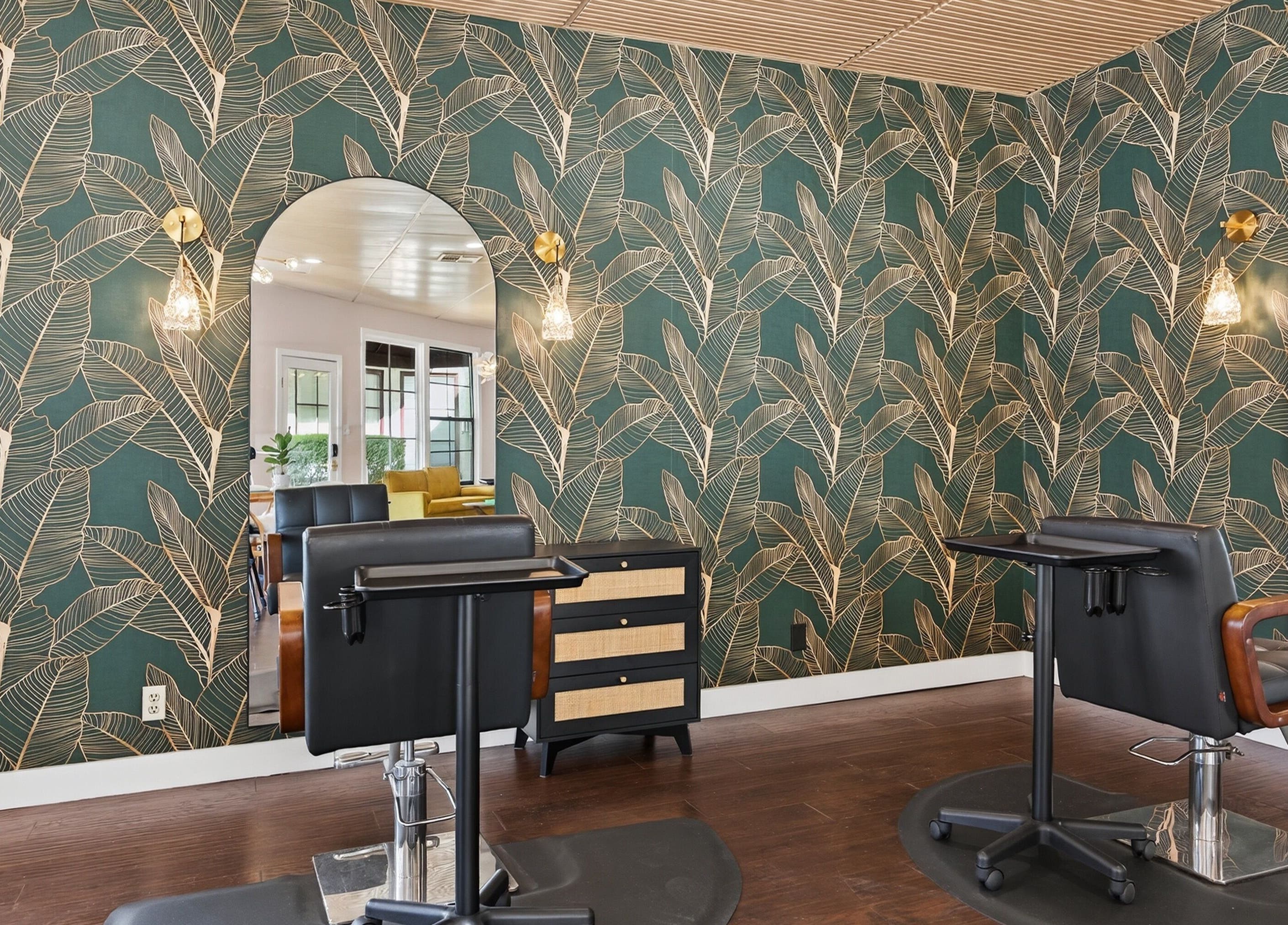 Chic hair salon interior at Bijou, Ojai, California, US with tropical wallpaper and stylish furnishings.