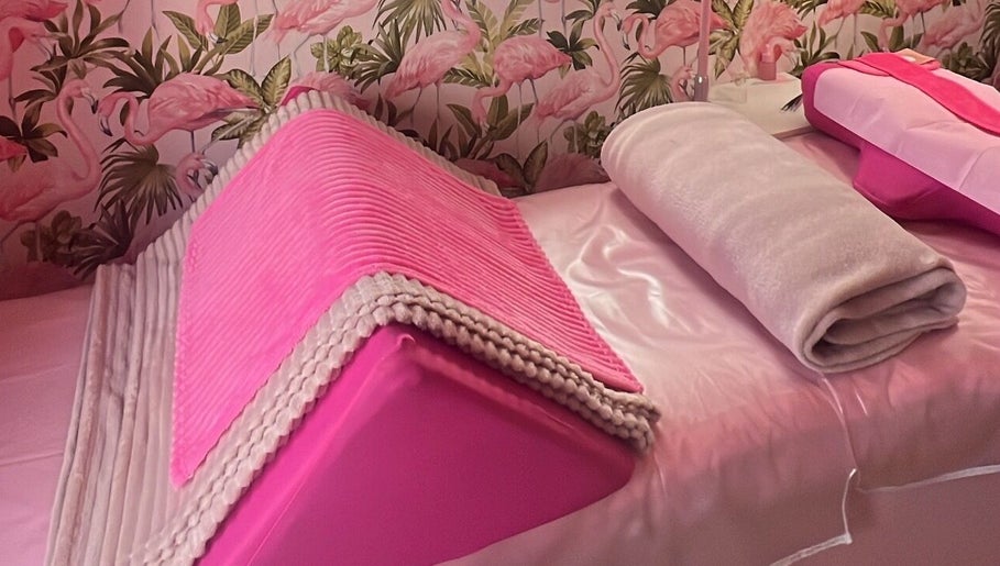 Relaxing pink treatment bed at Lashes by Leesh Bledington, Chipping Norton, England, GB with flamingo wallpaper.