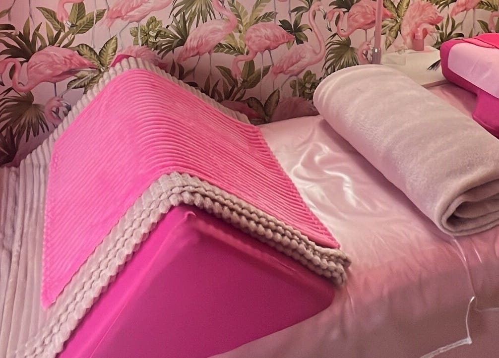Relaxing pink treatment bed at Lashes by Leesh Bledington, Chipping Norton, England, GB with flamingo wallpaper.