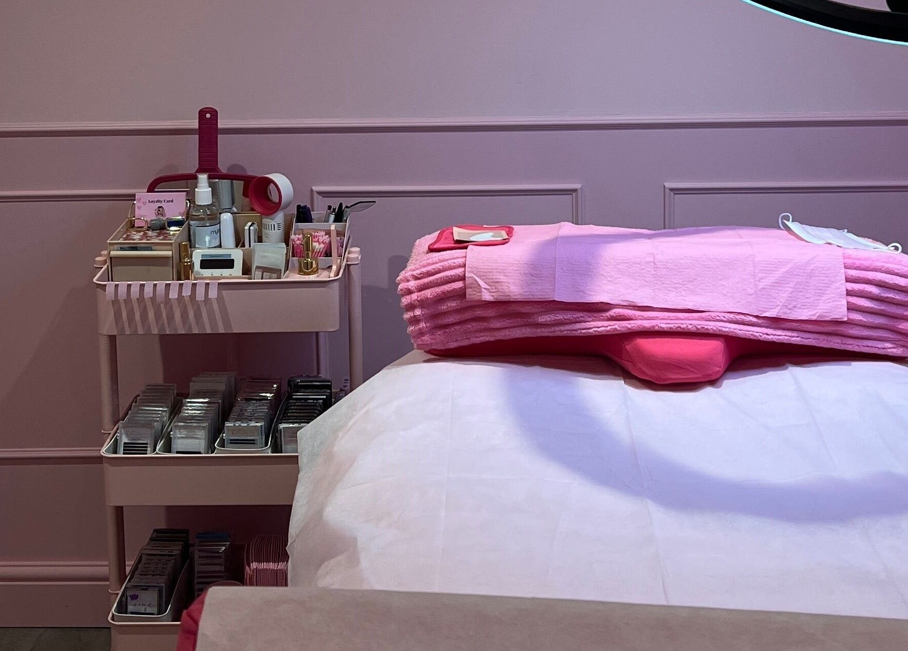 Cozy pink treatment room at Lashes By Leesh Witney, Witney, England, GB with neatly arranged beauty supplies.