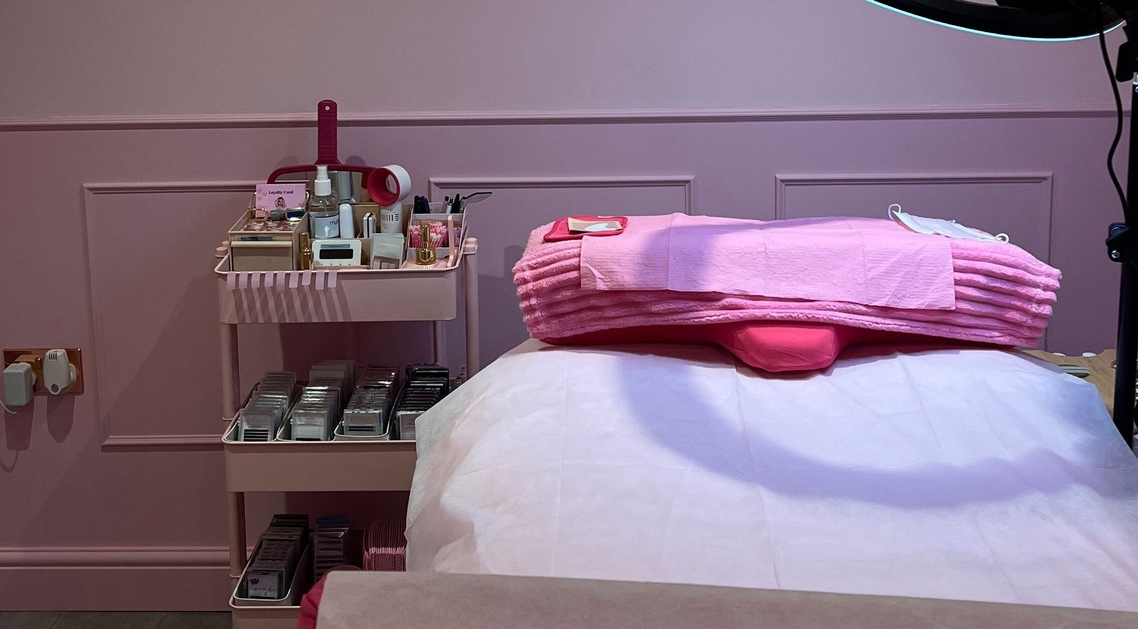 Cozy pink treatment room at Lashes By Leesh Witney, Witney, England, GB with neatly arranged beauty supplies.