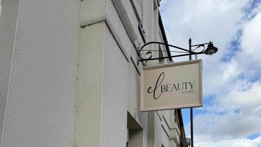 Exterior sign of El Beauty Studio in Market Deeping, England, GB, against a cloudy sky.