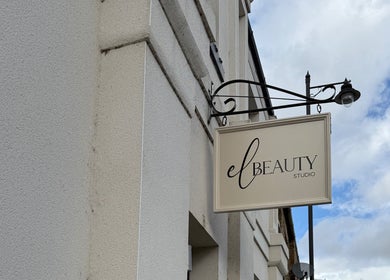 Exterior sign of El Beauty Studio in Market Deeping, England, GB, against a cloudy sky.