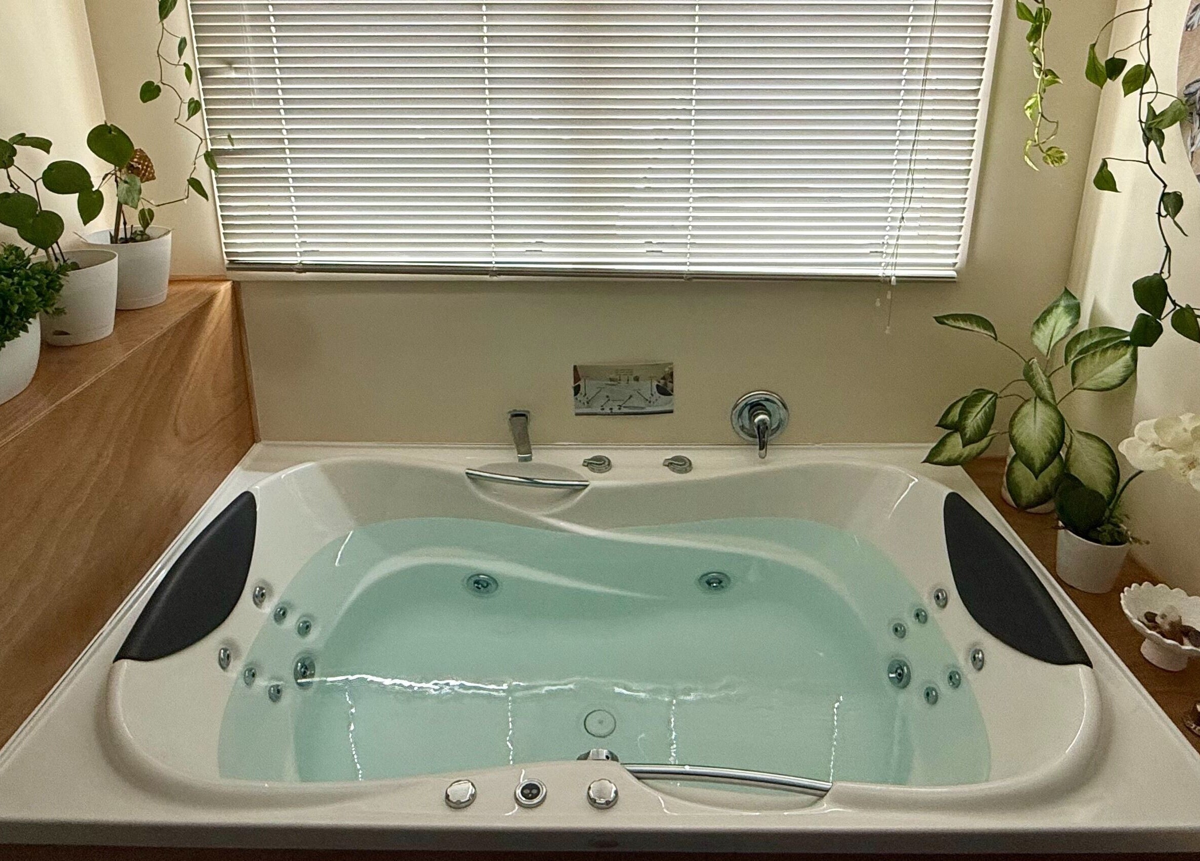 Relaxing spa tub at Te Whare O Kawakawa Spa, Fairfield, Hamilton, NZ, surrounded by greenery.