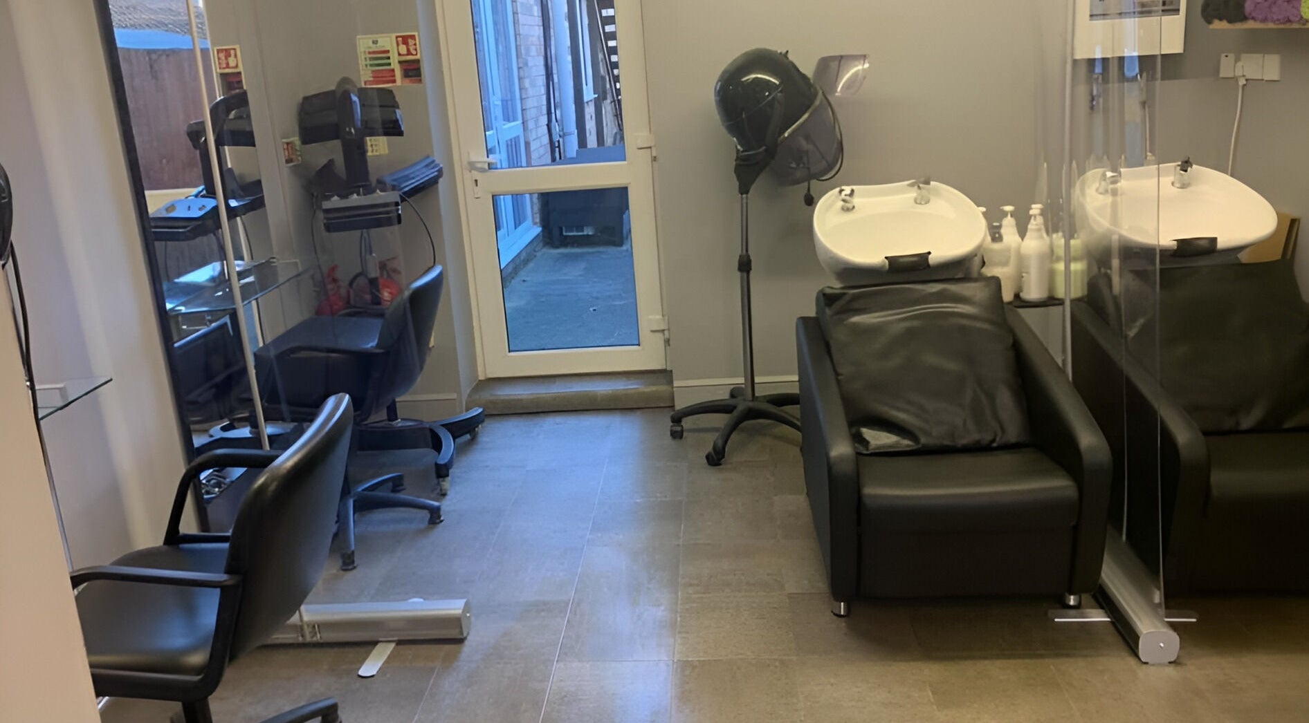 Modern hair salon at Headlines in Ramsey, England, GB featuring sleek black styling chairs and wash basins.