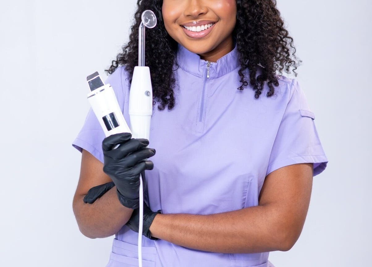 Skincare specialist at Ruellia Aesthetics Kingston, St. Andrew Parish, JM holding beauty tools, smiling confidently.