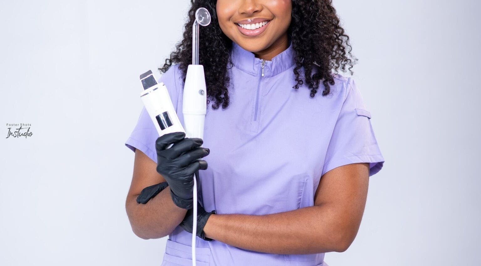 Skincare specialist at Ruellia Aesthetics Kingston, St. Andrew Parish, JM holding beauty tools, smiling confidently.