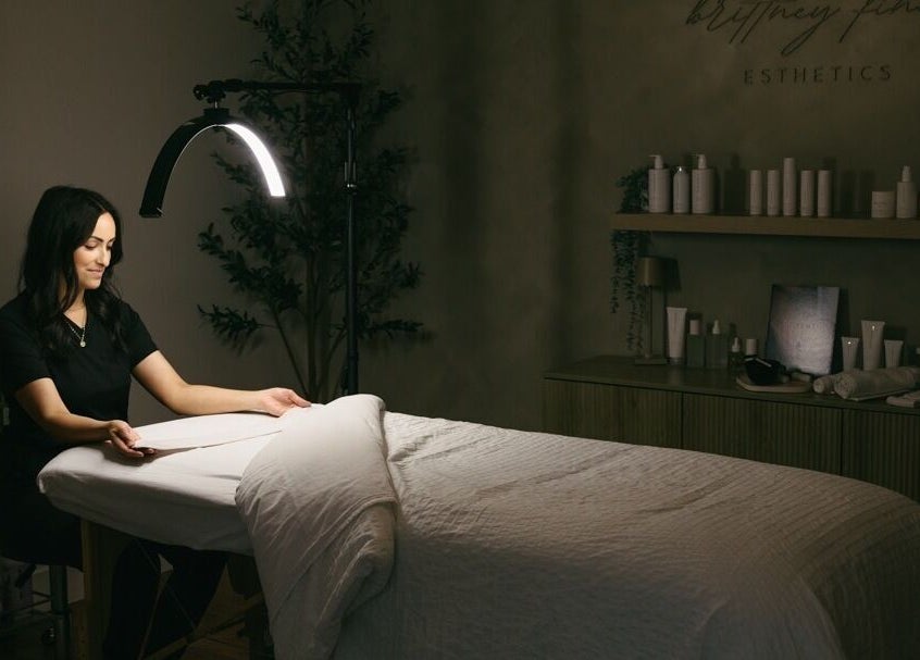 Calming spa room setup at Brittney Finch Esthetics, Ottawa, Ontario, CA, with therapist preparing the table.