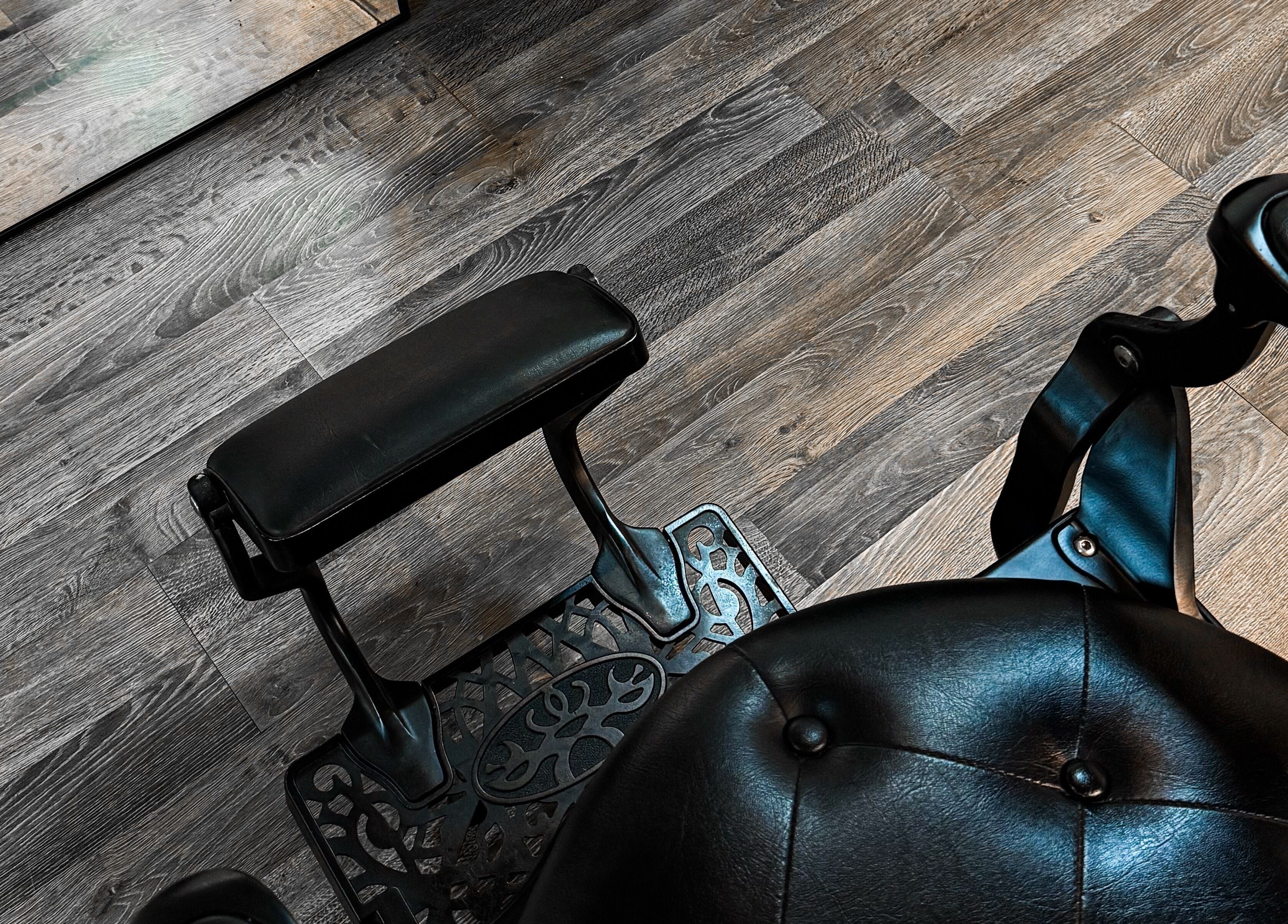 Elegant black leather barber chair at Mane Of Man, Singapore, Singapore, SG with stylish wooden flooring.