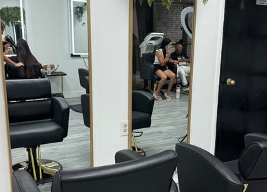 Modern salon interior at Shine by Bre, Orlando, Florida, US, showcasing sleek black chairs and large mirrors.