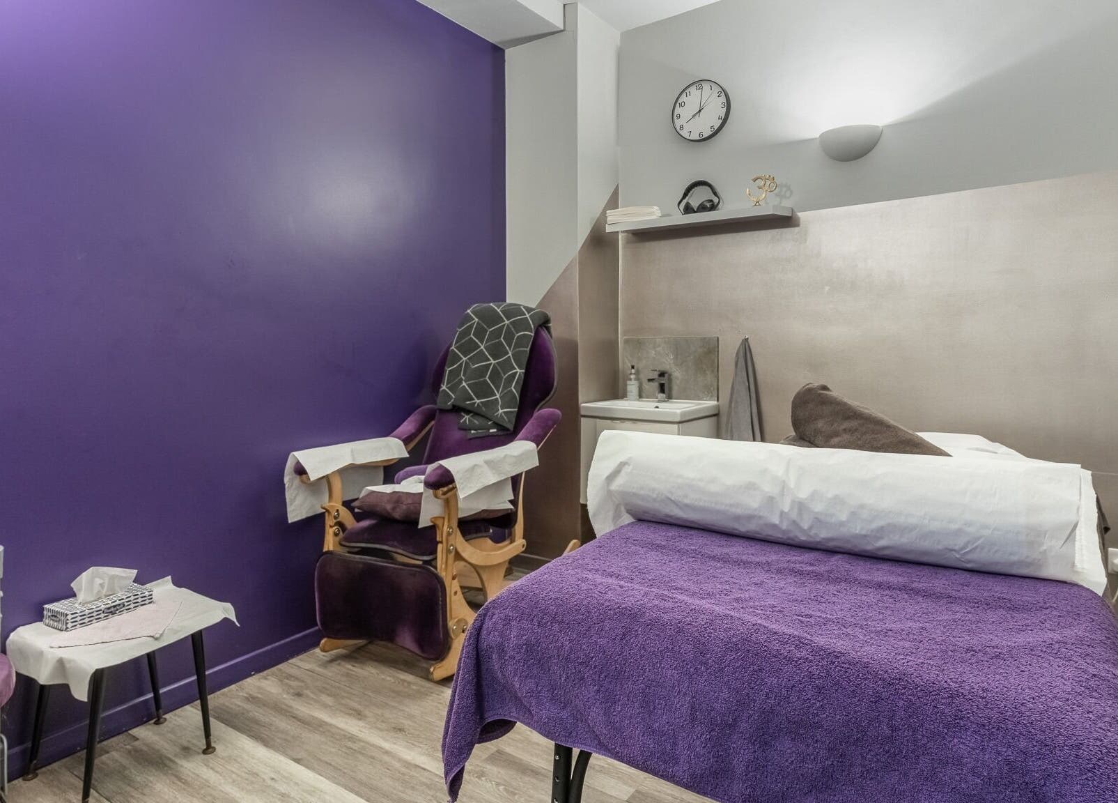 Reflexions Bayswater spa room with purple decor in London, England, GB, featuring massage table and chair.