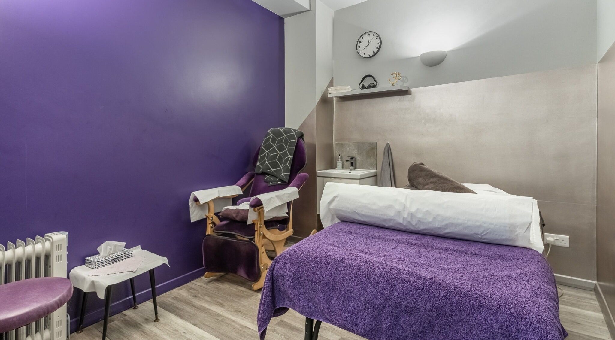 Reflexions Bayswater spa room with purple decor in London, England, GB, featuring massage table and chair.