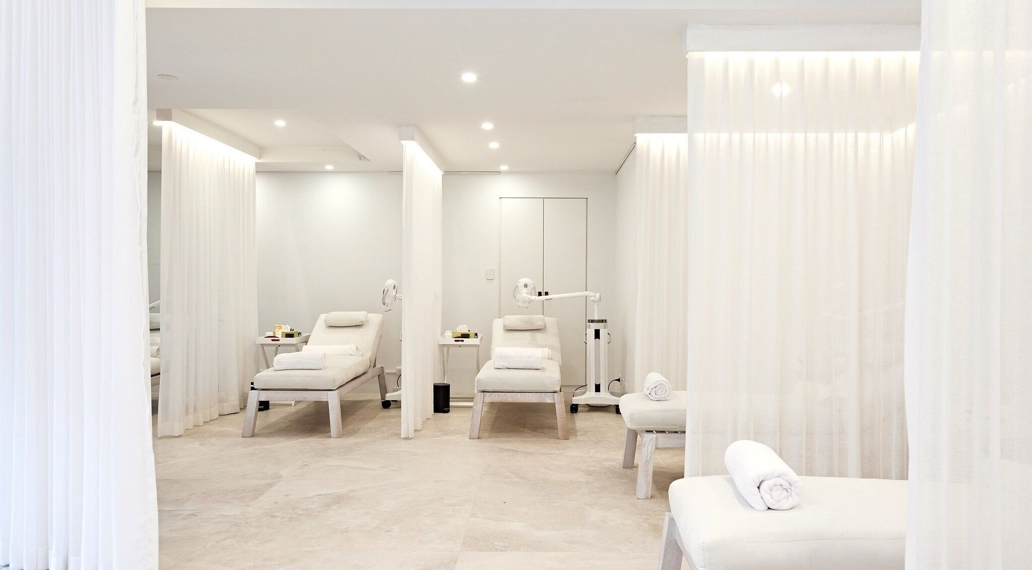 Elegant treatment room at The Whitening Clinic, Waverley, New South Wales, AU with plush white loungers and soft lighting.