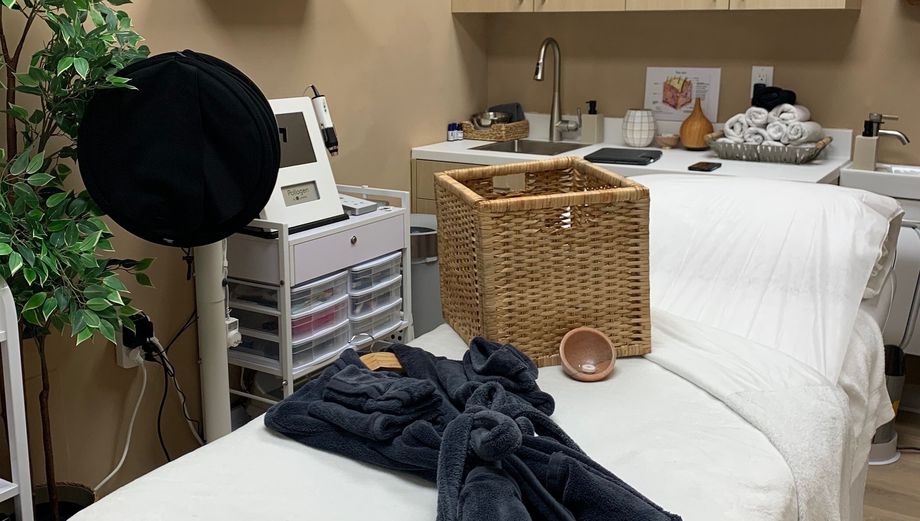 Cozy treatment room at Vertex Aesthetics in Toronto, Ontario, CA with plush white bed and elegant baskets.