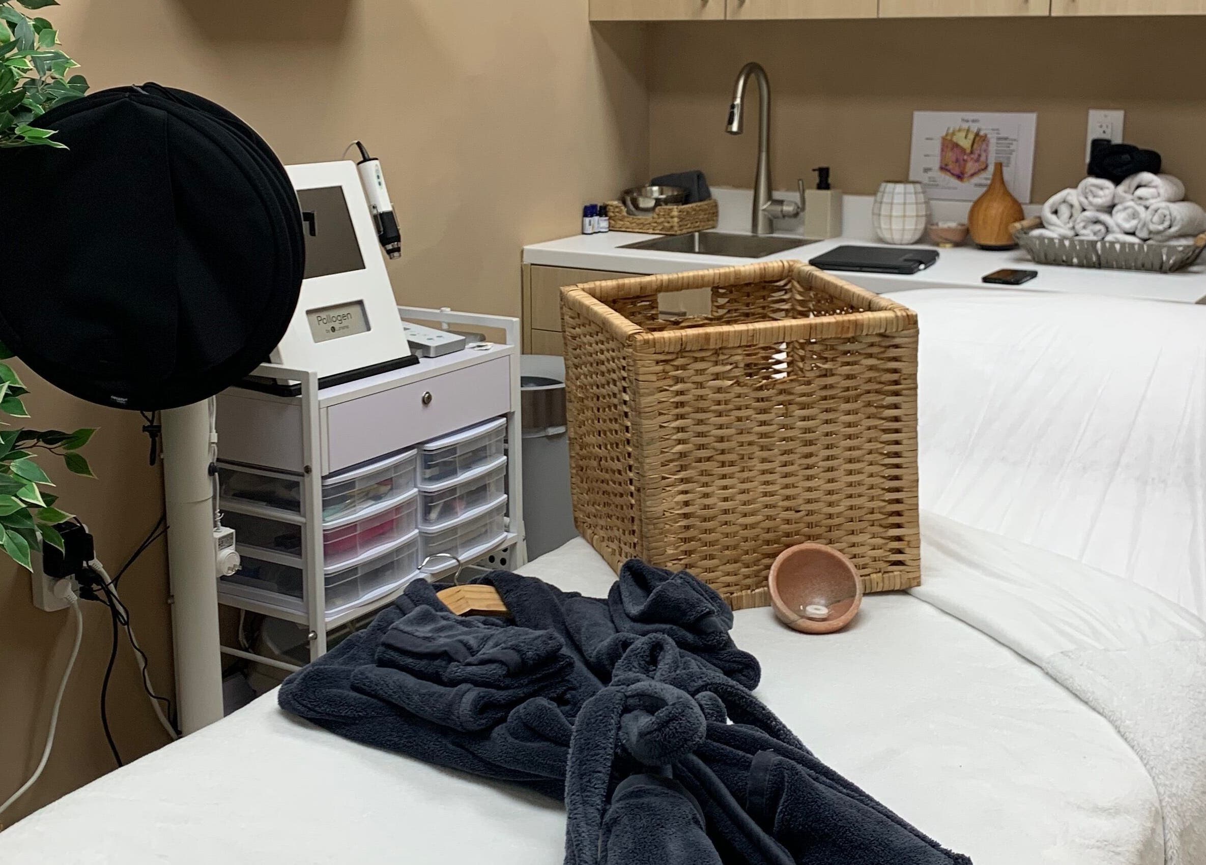 Cozy treatment room at Vertex Aesthetics in Toronto, Ontario, CA with plush white bed and elegant baskets.