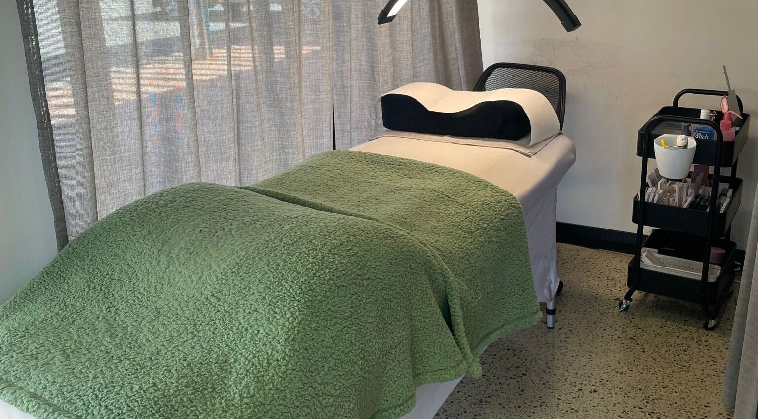 Relaxing treatment bed at All-Eyes Beauty, located in Falcon, Western Australia, AU, with a green cover.