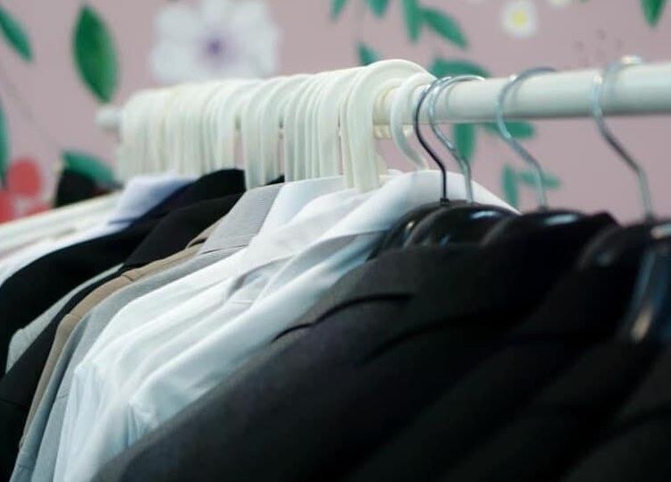 Elegant suits on hangers at Happy Face Photo Synthesis, Kowloon, HK, surrounded by floral decor.