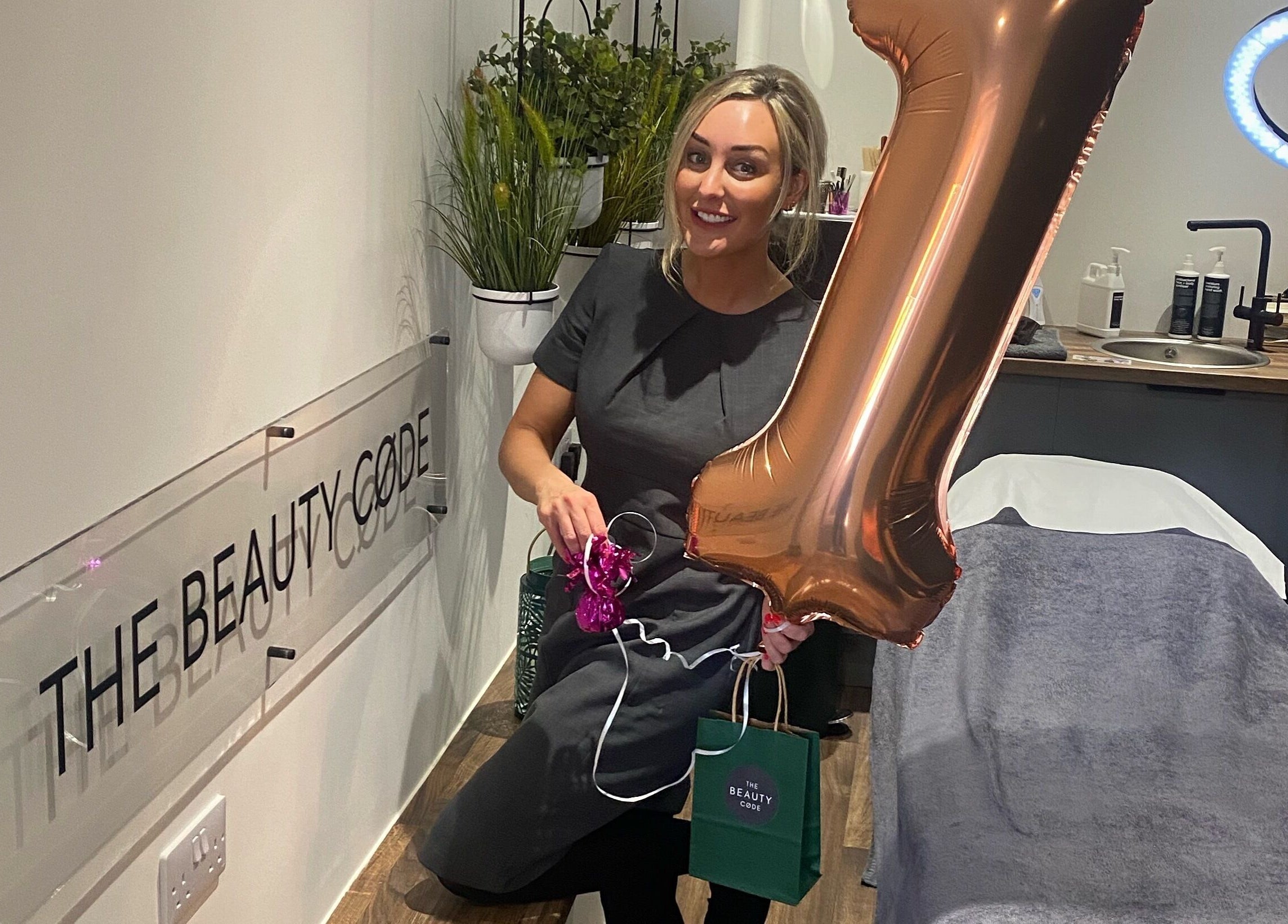 Staff member celebrating anniversary at The Beauty Code, St Austell, England, GB with decor and a balloon.