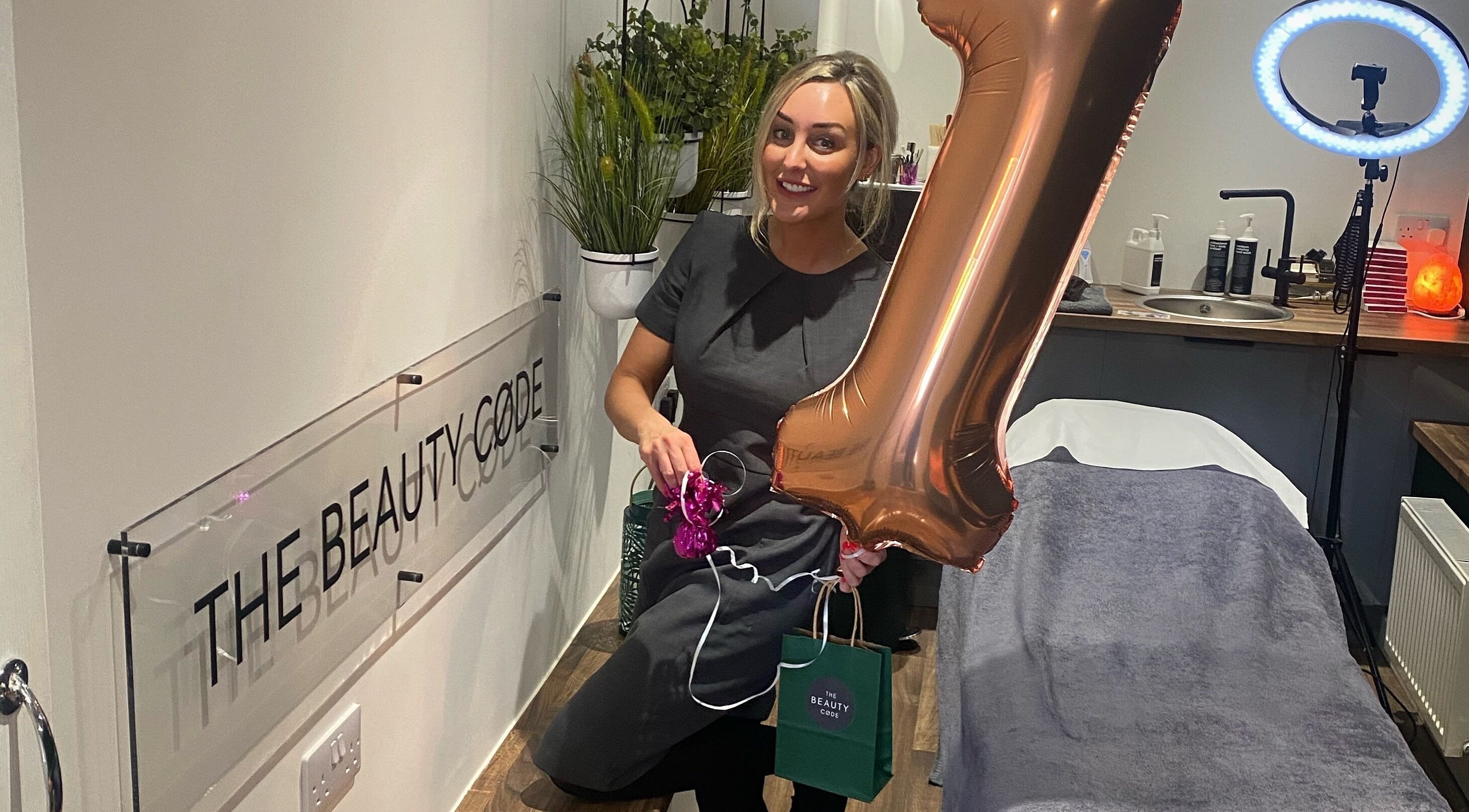 Staff member celebrating anniversary at The Beauty Code, St Austell, England, GB with decor and a balloon.