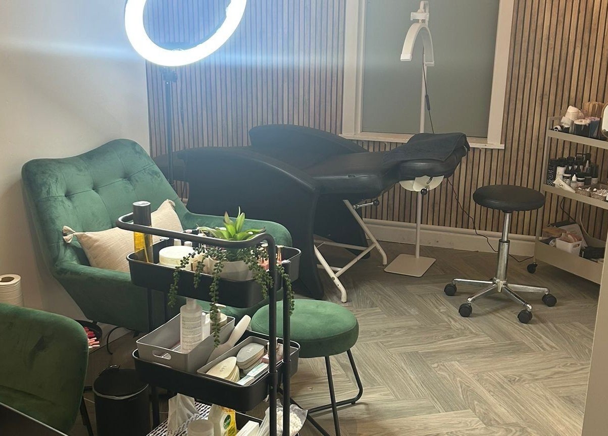 Chic treatment room at The Beauty Code, St Austell, England, GB with plush green seating and modern decor.