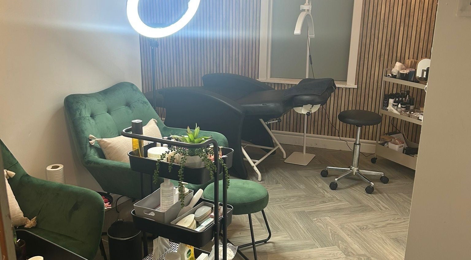Chic treatment room at The Beauty Code, St Austell, England, GB with plush green seating and modern decor.