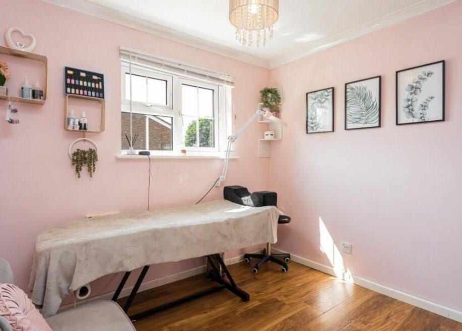 Relaxing treatment room at Ellie’s Lash Extensions in Copthorne, England with pink decor and cozy bed.