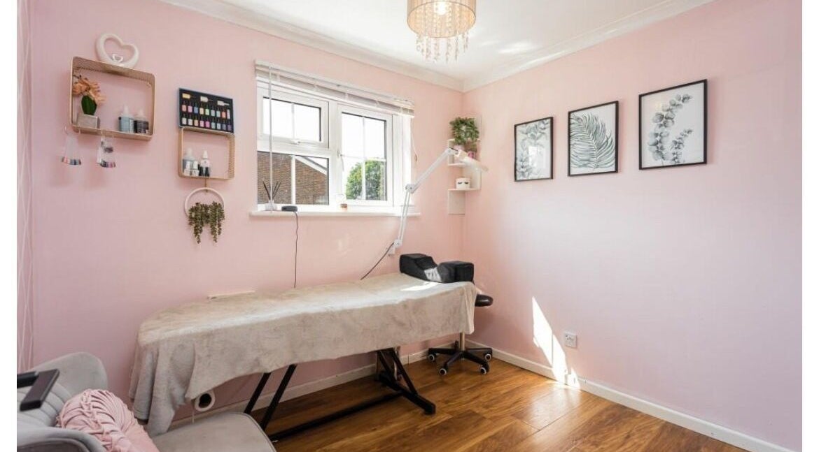 Relaxing treatment room at Ellie’s Lash Extensions in Copthorne, England with pink decor and cozy bed.