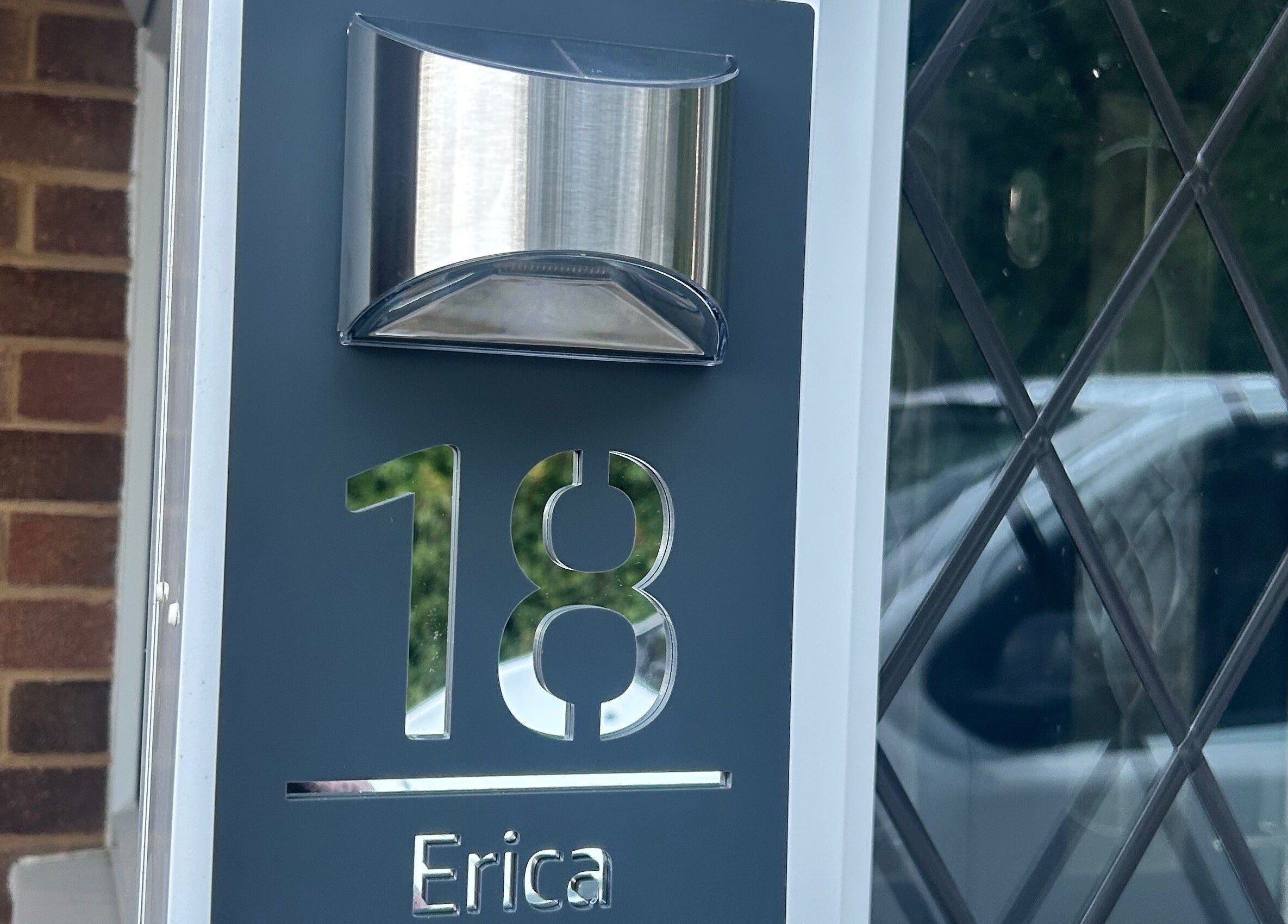 Modern entrance sign at Ellie’s Lash Extensions, Copthorne, England, GB, with building reflection.