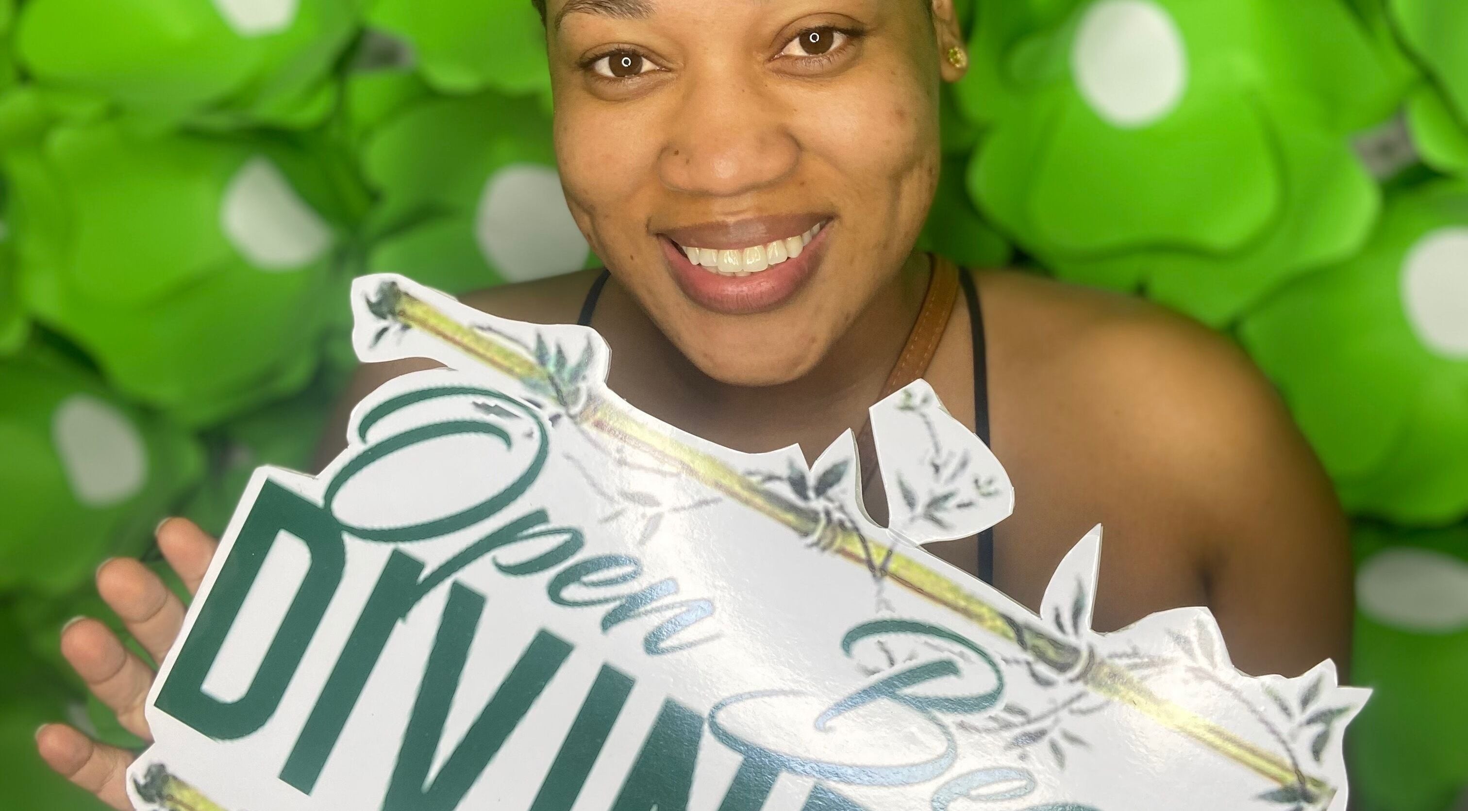 Smiling woman holds Open Beauty Divine Spa sign, Kingston, St. Andrew Parish, JM.