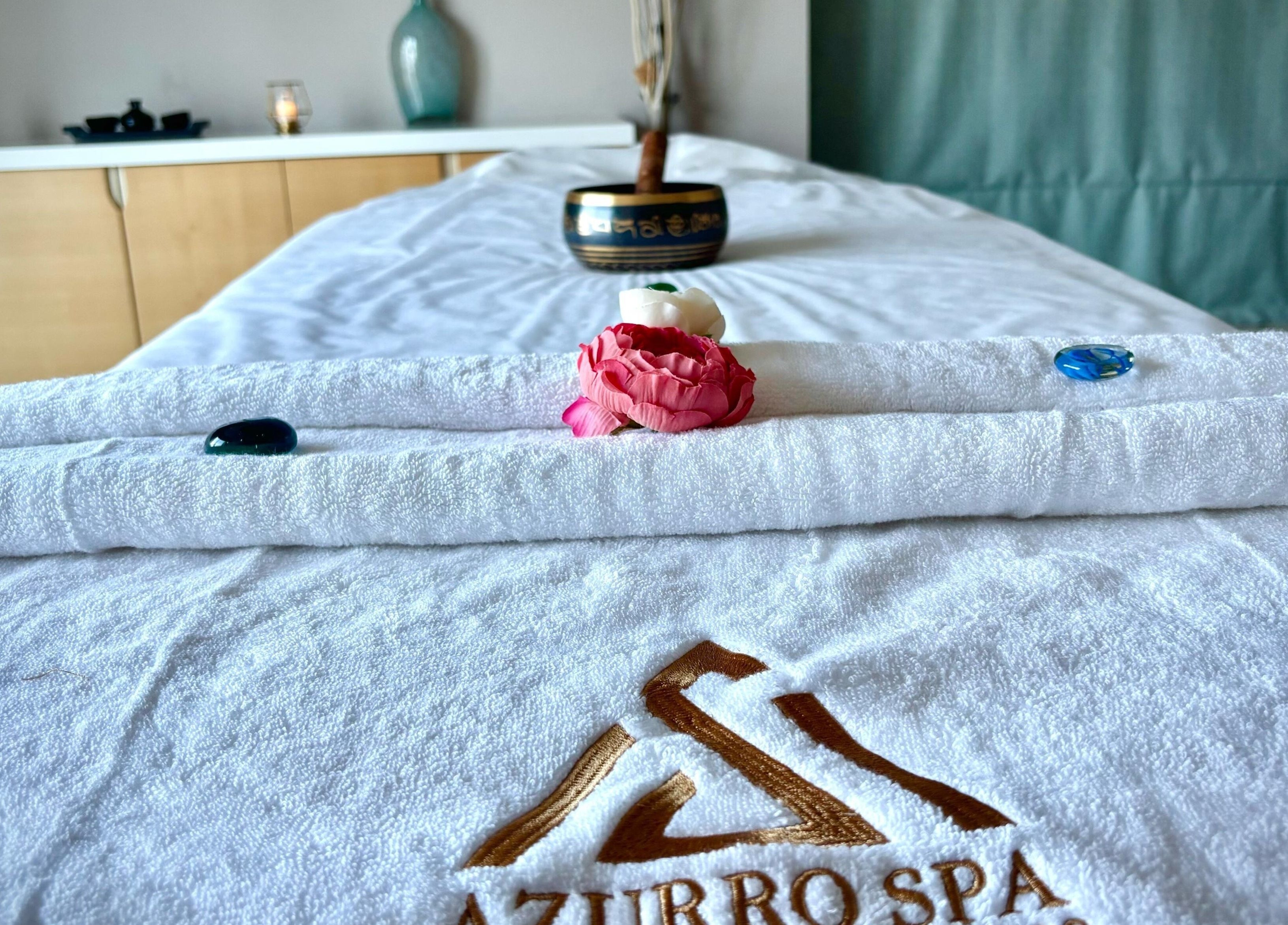 Massage table at Azurro Spa by Niyama - Pullman Hotel Jlt, Dubai, Dubai, AE with towels and flowers.