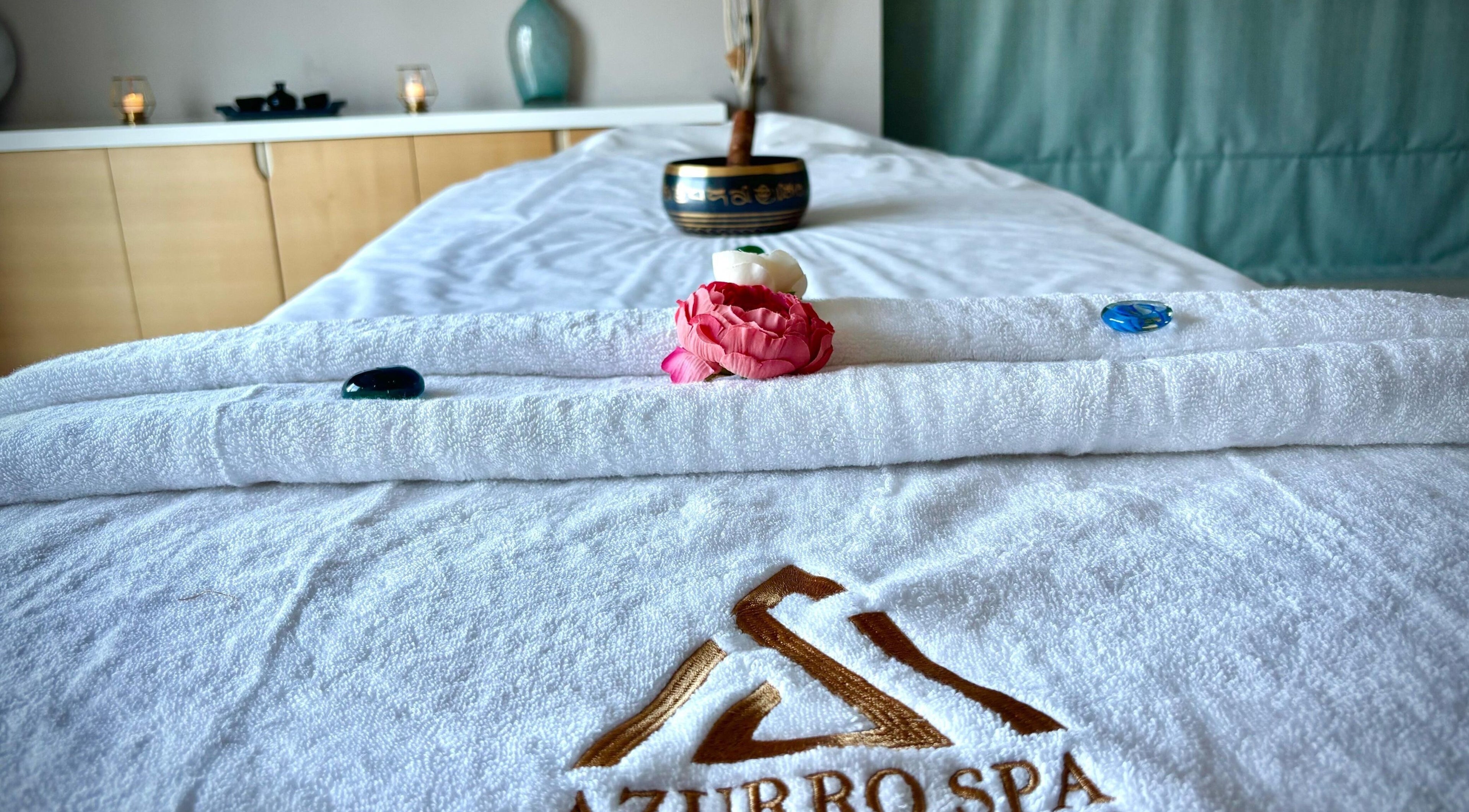 Massage table at Azurro Spa by Niyama - Pullman Hotel Jlt, Dubai, Dubai, AE with towels and flowers.