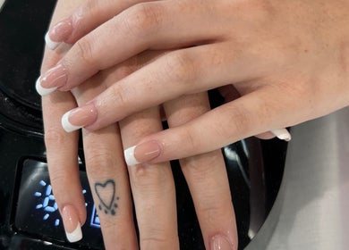 Elegant French manicure at Helen's Nails & Spa, Wildwood, Florida, US. Classic nail art with a tattoo accent.