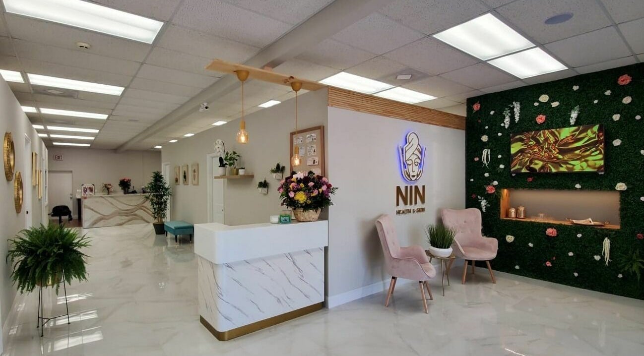 Reception area of NIN Health and Skin in Sarasota, Florida, US, featuring modern decor and lush greenery.