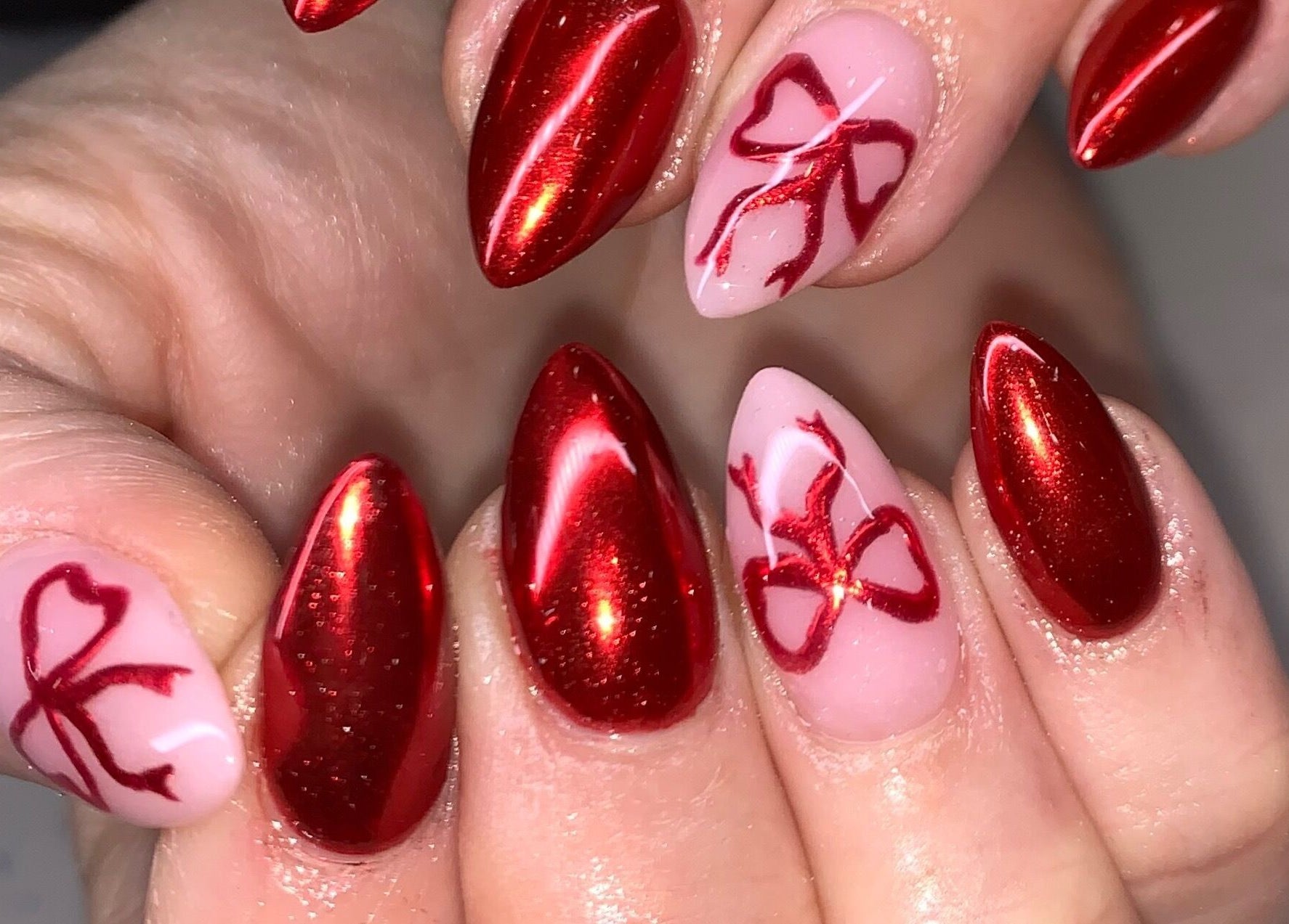 Elegant red nails with bow art at Luxx Nails & Spa, Canonsburg, Pennsylvania, US.